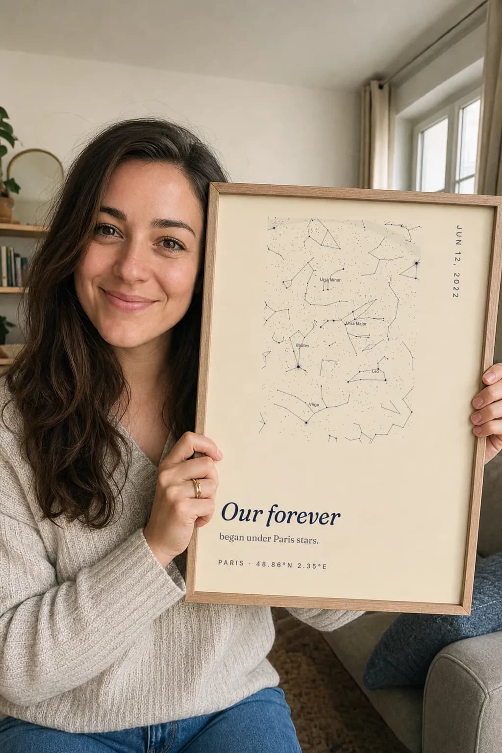 A woman holding up a framed SkyWhen star map print
